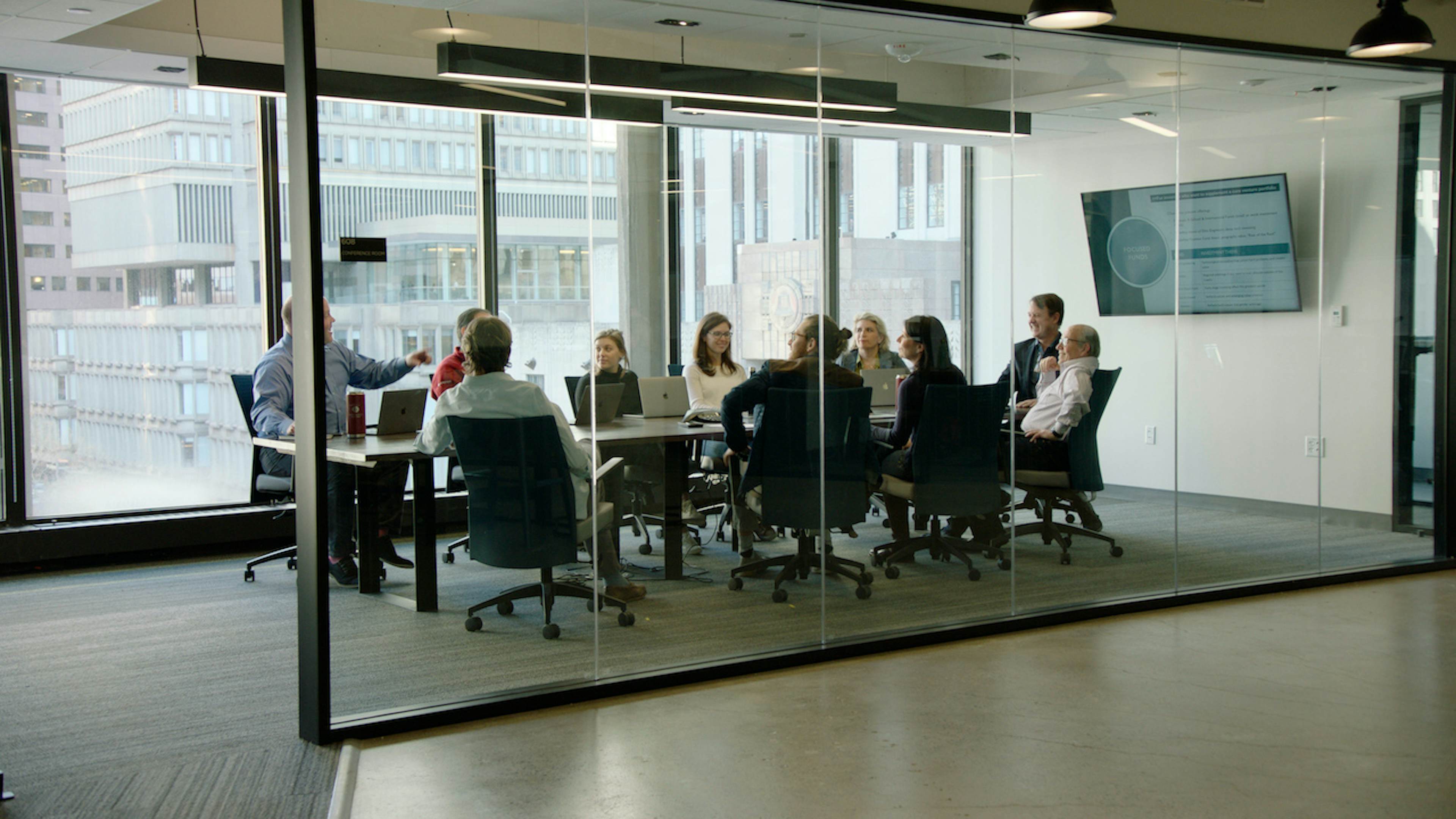 People attending a large meeting in office setting